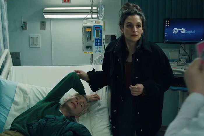 A woman in a hospital room standing beside a patient in bed, conveying a poignant moment.
