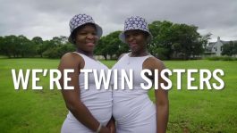 Twin sisters in white dresses and bucket hats.