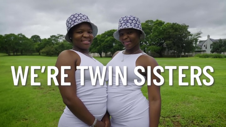 Twin sisters in white dresses and bucket hats.