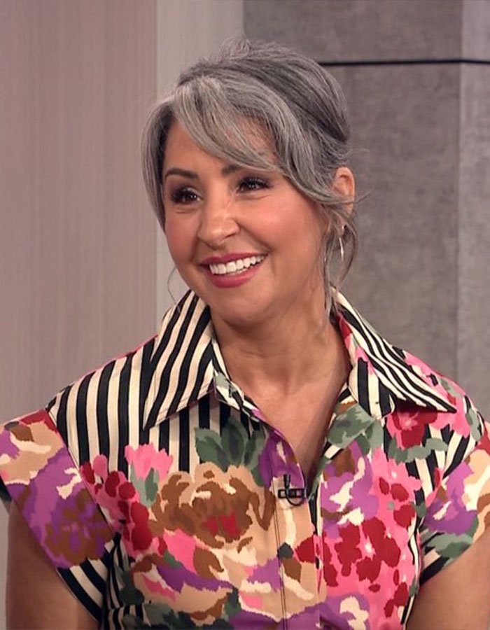 Smiling woman with gray hair and floral dress shares inspiring life story after cancer diagnosis.